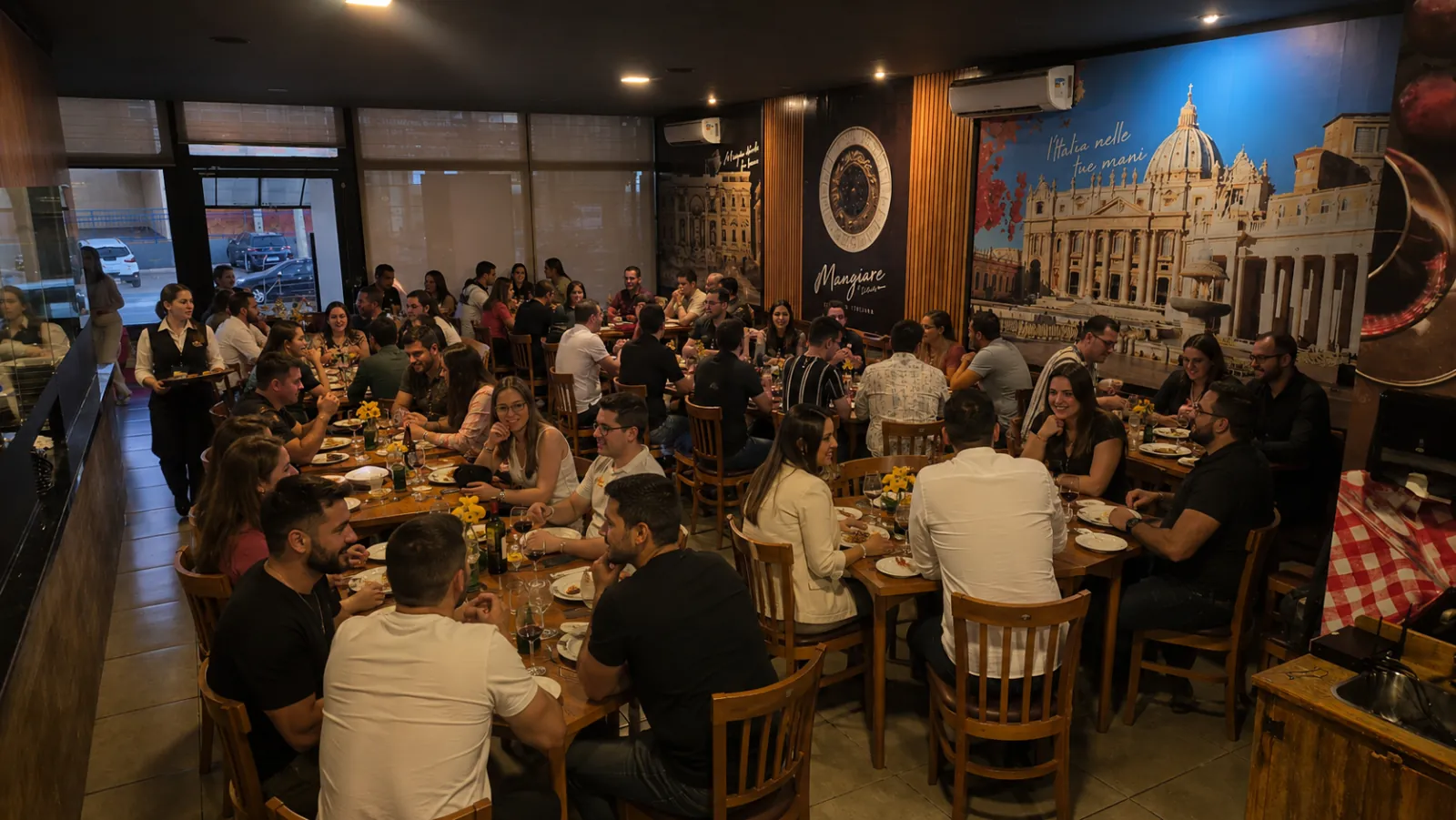 Salão do Mangiare Ristorante cheio de clientes jantando, com mesas de madeira, luz aconchegante e painéis da Itália nas paredes